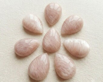 May include: Eight teardrop-shaped cabochons arranged in a circular pattern. Each stone features a smooth, polished surface with a soft, pale pink hue and a subtle, fibrous chatoyant sheen that creates a delicate, light-reflecting appearance.