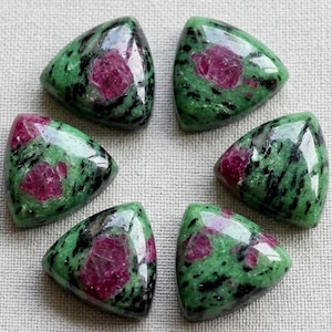 May include: Six polished, triangular-shaped cabochons of zoisite with embedded ruby crystals. Each stone features a vibrant green base with distinct black hornblende inclusions and opaque, deep pink to magenta ruby patches throughout the surface.
