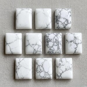 May include: Ten rectangular cabochons made of white stone with grey veining. Each piece features a smooth, polished surface with unique, natural-looking crackled patterns in varying shades of grey distributed across the white base material.