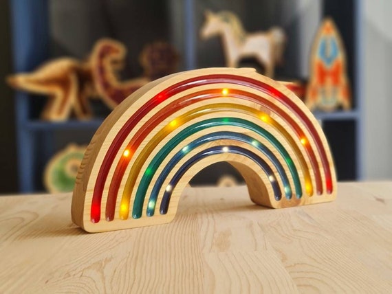 Montessori-style wooden rainbow lamp illuminating a colorful playroom.