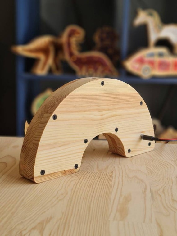 Minimalist wooden rainbow lamp glowing softly on a shelf.