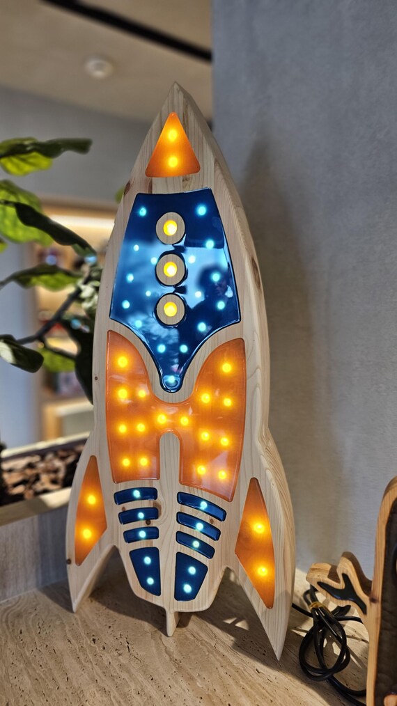 Vertical rocket LED lamp glowing in yellow and blue tones beside star decor