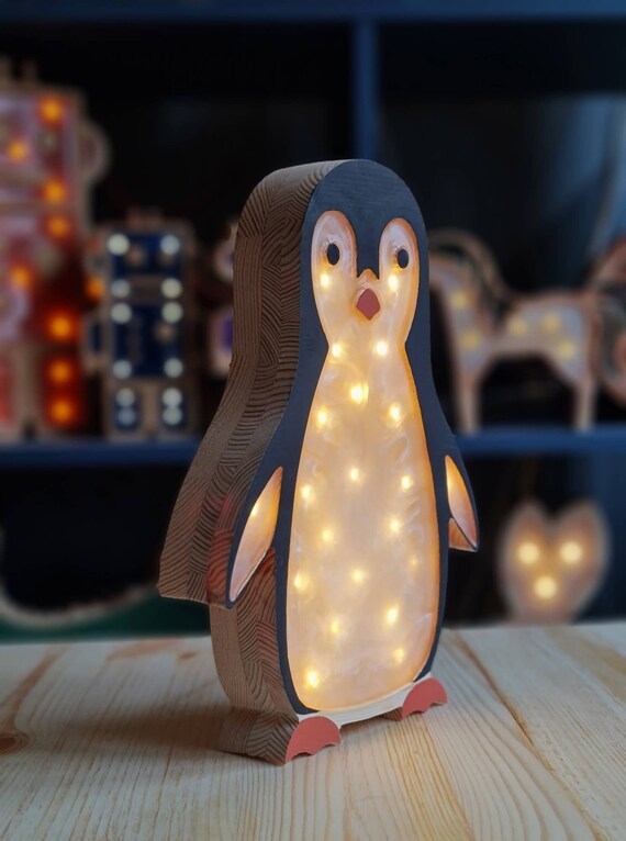 Wooden penguin night light glowing softly on a wooden table