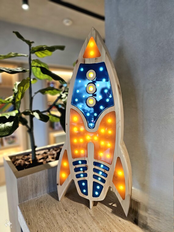 Illuminated rocket ship night light enhancing a dark-themed children’s bedroom