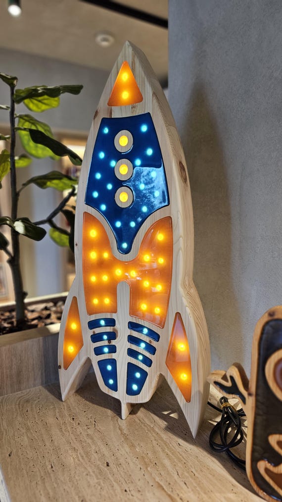 Space-themed rocket night light placed beside a star cushion and toy car