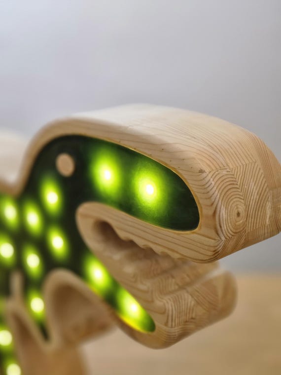 Remote control next to a glowing dinosaur lamp for kids’ bedrooms