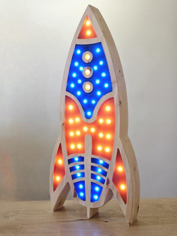 Large 85 cm rocket lamp beside a yellow star pillow in kids room.