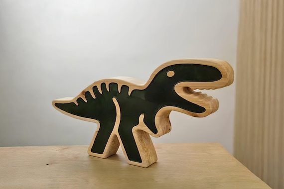 Green dinosaur-shaped wooden LED night light glowing on a wooden surface