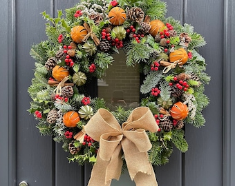 Real Handmade Christmas Wreath with foliage, holly, cones, cinnamon sticks, dried limes and oranges, berries and hessian bow.