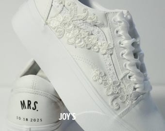 May include: White sneakers with floral lace and pearl embellishments. The shoes feature satin ribbon laces and the text "MRS. 10 18 2025" on the heel. The brand logo is visible on the sole.