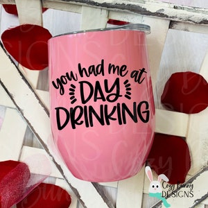 Pode incluir: Um copo de vinho de a&ccedil;o inoxid&aacute;vel rosa com texto preto que diz "You had me at day drinking".