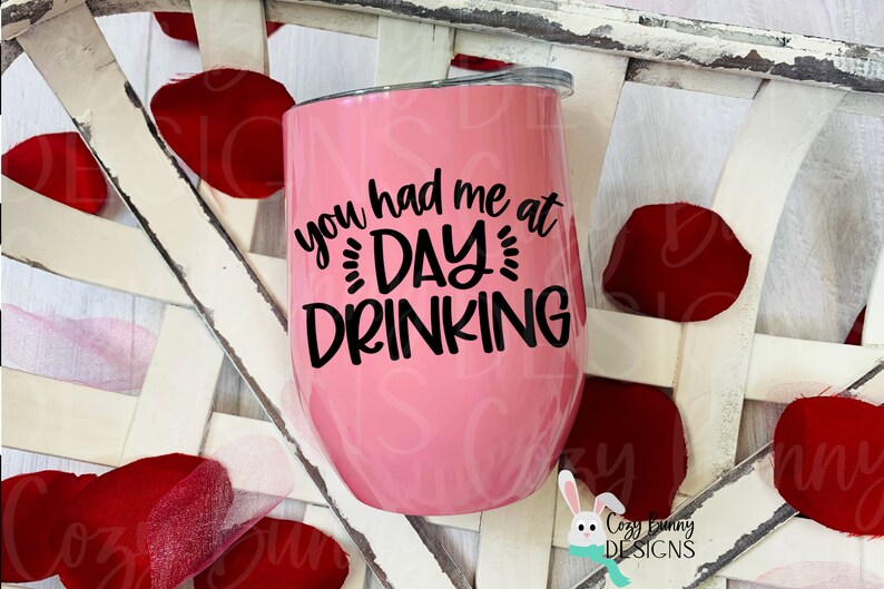 Pode incluir: Um copo de vinho de a&ccedil;o inoxid&aacute;vel rosa com texto preto que diz "You had me at day drinking".