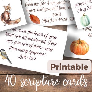 May include: A collection of forty rectangular white cards featuring printed scripture verses in a dark brown script font. Each card is decorated with watercolor illustrations including a fox, a bird, a red leaf, and orange and green pumpkins.