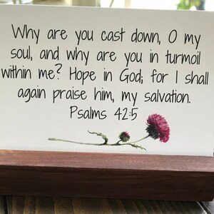 May include: A white card with a bible verse from Psalms 42:5, "Why are you cast down, O my soul, and why are you in turmoil within me? Hope in God; for I shall again praise him, my salvation." The card has a watercolor illustration of a purple thistle.