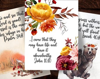 Könnte beinhalten: Drei rechteckige Drucke mit Aquarell-Blumenarrangements und schwarzem Schrifttext. Der mittlere Druck zeigt den Text 'I came that they may have life and have it abundantly. John 10:10' mit gelben, orangefarbenen und dunkelroten Blumen.
