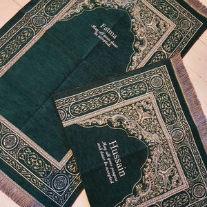 Op de afbeelding: Twee groene gebedskleden met sierlijke zilveren en gouden ontwerpen. E&eacute;n kleed is rechthoekig, de andere kleiner met een gewelfde bovenkant. Tekst op de kleden luidt "Fatma, Mogen al je dua's geaccepteerd worden" en "Hussain, Mogen al je gebeden en dua's geaccepteerd worden."