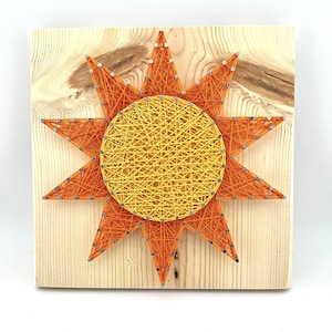 May include: A handmade sun string art piece. The sun design features a yellow center and orange rays, all crafted with string and nails on a light-colored wooden board. The artwork is a square shape and is suitable for wall decor.