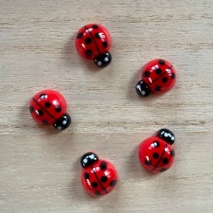 May include: Five red and black ladybug shaped buttons with black dots.