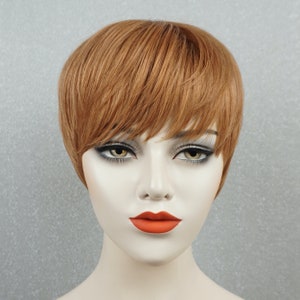 May include: A short, straight, auburn-colored wig with bangs. The wig is styled on a mannequin head.