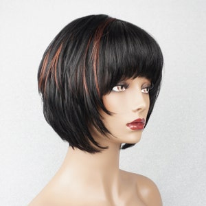 Op de afbeelding: Een kort zwart pruik met subtiele roodbruine highlights. De pruik heeft een rechte, stompe snit met een pony.