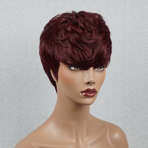 May include: A short, choppy, burgundy-colored wig with a side part and a textured, wavy style.