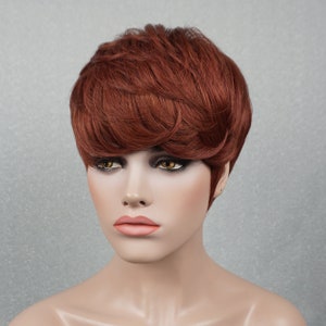 May include: A short, choppy, auburn-colored wig with a side part. The wig is styled with a layered, textured look.