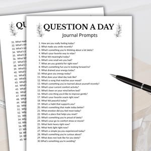 Może przedstawiać: Dwie białe strony z tekstem "QUESTION A DAY Journal Prompts" i numerowanymi pytaniami. Czarny długopis ze srebrną końc&oacute;wką spoczywa na stronach. Strony znajdują się na jasnej drewnianej powierzchni.