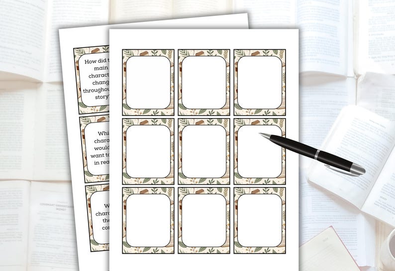 May include: Two sheets of printed cards with a decorative border, featuring blank spaces for writing. The cards have text prompts like "How did the main character change throughout the story?" A black pen rests on the cards, suggesting note-taking or writing.