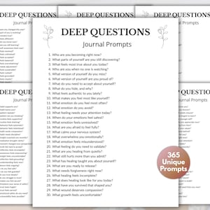May include: A stack of white journal pages with the text "DEEP QUESTIONS Journal Prompts" and a list of questions. A circular sticker reads "365 Unique Prompts". The pages have a minimalist design with floral accents.