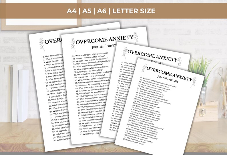 K&ouml;nnte beinhalten: Vier wei&szlig;e Papierb&ouml;gen mit dem Titel OVERCOME ANXIETY Journal Prompts in schwarzer Schrift, begleitet von kleinen Blumenillustrationen. Die Seiten enthalten nummerierte Fragen zur Selbstreflexion, erh&auml;ltlich in den Formaten A4, A5, A6 und Letter.