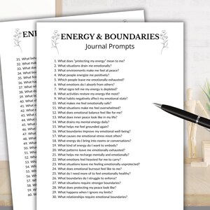 May include: Two white sheets of paper with the text "ENERGY & BOUNDARIES Journal Prompts" and a list of questions. A black pen rests on the right side of the paper. The papers are on a wooden desk.