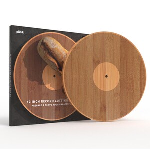 K&ouml;nnte beinhalten: Ein 30 cm gro&szlig;es Schneidebrett in Form einer Schallplatte aus Holz. Die Verpackung ist schwarz mit dem Text "12 INCH RECORD CUTTING BOARD" und "PREPARE & SERVE YOUR GREATEST".