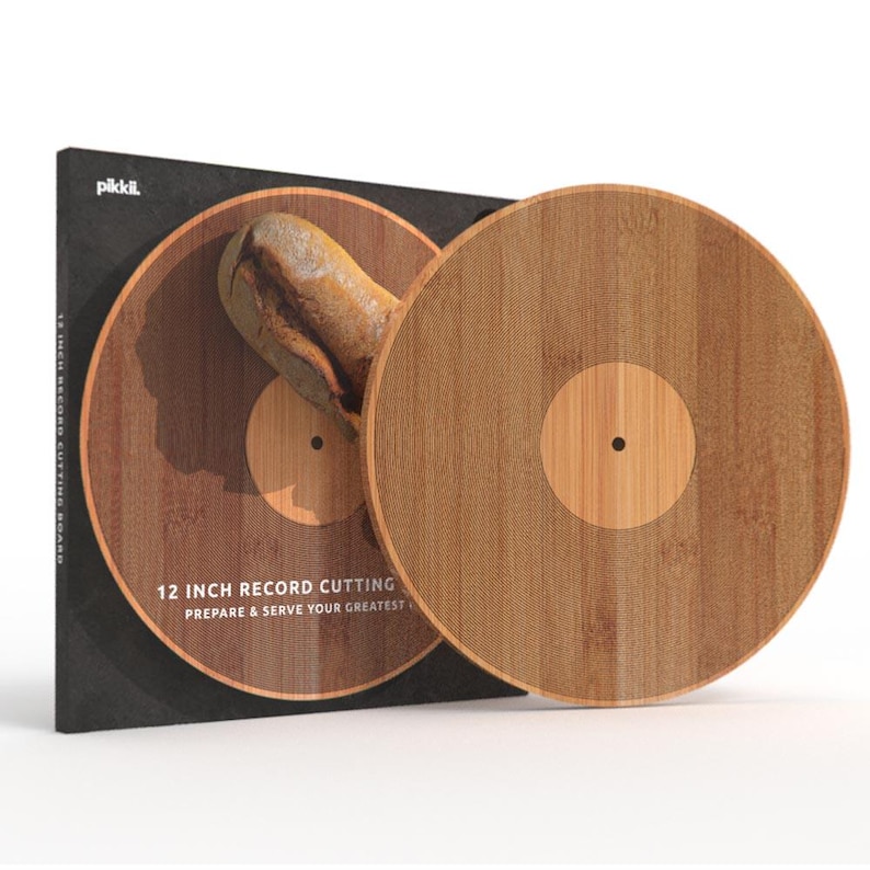 K&ouml;nnte beinhalten: Ein 30 cm gro&szlig;es Schneidebrett in Form einer Schallplatte aus Holz. Die Verpackung ist schwarz mit dem Text "12 INCH RECORD CUTTING BOARD" und "PREPARE & SERVE YOUR GREATEST".