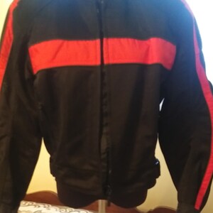 May include: Black motorcycle jacket with red accents. The jacket has a zipper closure and a stand-up collar.
