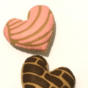 May include: Two felt heart-shaped pillows, one pink with brown stripes and one brown with brown stripes.
