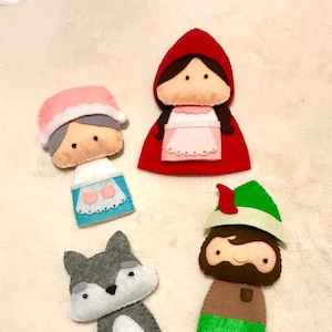Puede incluir: Conjunto de cinco marionetas de dedo de fieltro con personajes del cuento de hadas Caperucita Roja. Las marionetas incluyen a Caperucita Roja, el lobo, la abuela y el leñador. Las marionetas están todas cosidas a mano y tienen un aspecto caprichoso y hecho a mano.