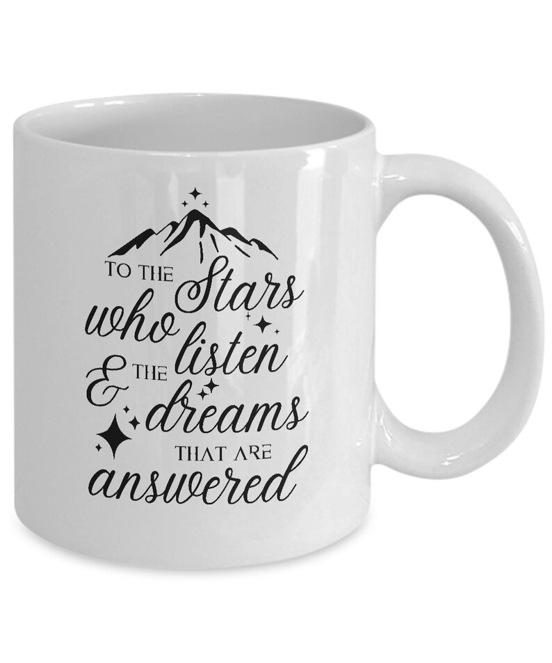 May include: White ceramic coffee mug with a black design that reads "To the stars who listen & the dreams that are answered". The design also includes a mountain range and stars.