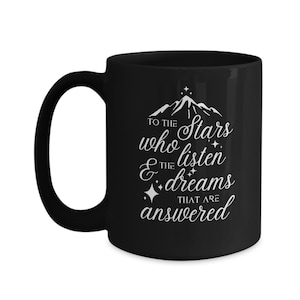 May include: Black ceramic coffee mug with a white design that reads "To the stars who listen & the dreams that are answered".