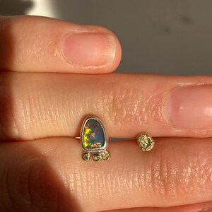 Puede incluir: Un pendiente de plata y oro con una piedra de &oacute;palo en forma de l&aacute;grima y peque&ntilde;as cuentas doradas alrededor de la piedra.