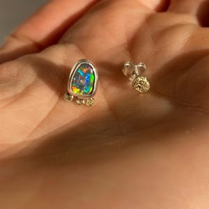 Puede incluir: Un par de pendientes de plata con una piedra preciosa de &oacute;palo en forma de l&aacute;grima y detalles dorados.