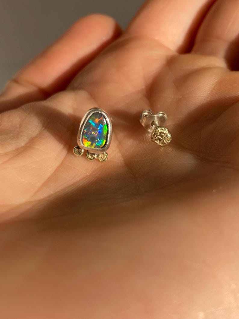 Puede incluir: Un par de pendientes de plata con una piedra preciosa de &oacute;palo en forma de l&aacute;grima y detalles dorados.