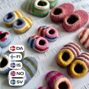 Könnte beinhalten: Eine Sammlung kleiner Hausschuhe aus gefilzter Wolle in verschiedenen Farbkombinationen, darunter grün-rosa Streifen, einfarbiges Rosa, gelb-blaue Streifen, mehrfarbige Streifen sowie blau-grüne Streifen, angeordnet auf einer weißen, strukturierten Oberfläche.