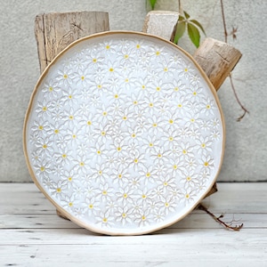 Könnte beinhalten: Weiße Keramik-Servierplatte mit einem erhabenen Design aus kleinen gelben Blumen.