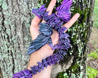 May include: A purple and black crystal dragon sculpture with wings outstretched. The dragon is made of many small, faceted pieces of crystal.