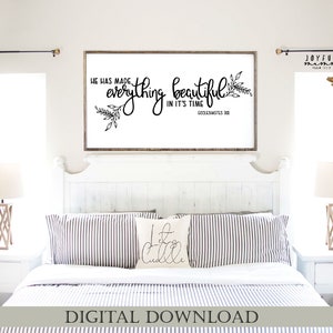 May include: A white bedroom with a white bed frame and a black and white striped duvet. A framed print with the text "He has made everything beautiful in it's time" hangs on the wall above the bed. There are two lamps on bedside tables on either side of the bed.