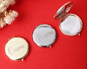 May include: Three compact mirrors with personalized engravings. The mirrors are gold, silver, and rose gold. The engravings read "Caro", "Picasso", and a blank mirror.