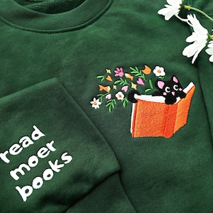 Sudadera con gato bordado acostado sobre un libro y flores, sudadera con gato negro, cuello redondo con margaritas bordadas, sudadera de lectura, regalos para amantes de los gatos