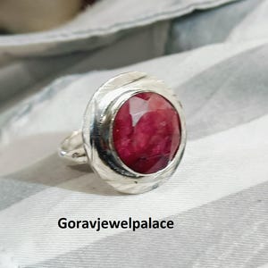Può includere: Un anello d'argento con una grande pietra ovale rossa incastonata in una fascia d'argento testurizzata.