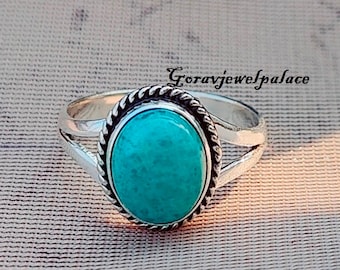 Può includere: Un anello d'argento con una pietra ovale turchese incastonata in un bordo a forma di corda. L'anello ha una montatura divisa.