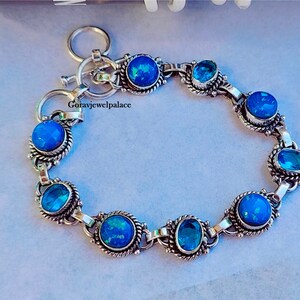 May include: A silver bracelet with alternating blue opal and blue topaz stones. The bracelet has a toggle clasp.